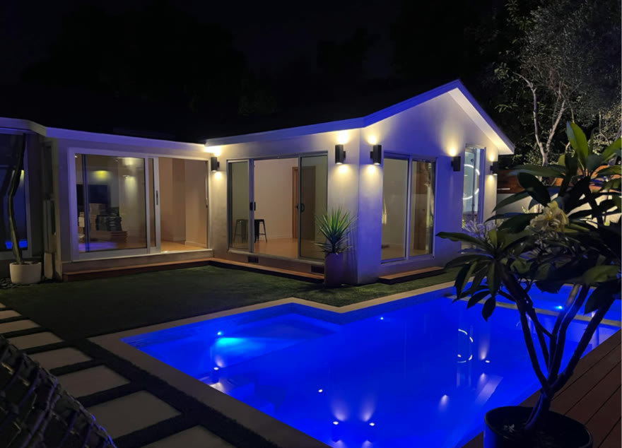 Florent's pool glowing blue at night beside his modern Los Angeles home